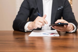 Person holding a phone and a pen.